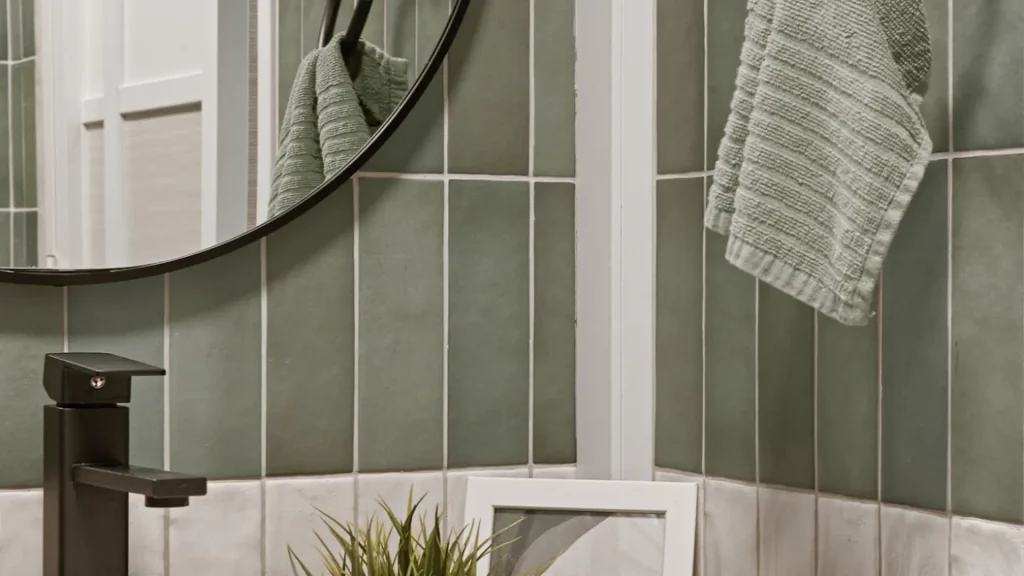 Sage green tiles and timber vanity with matte black fixtures in HDB bathroom