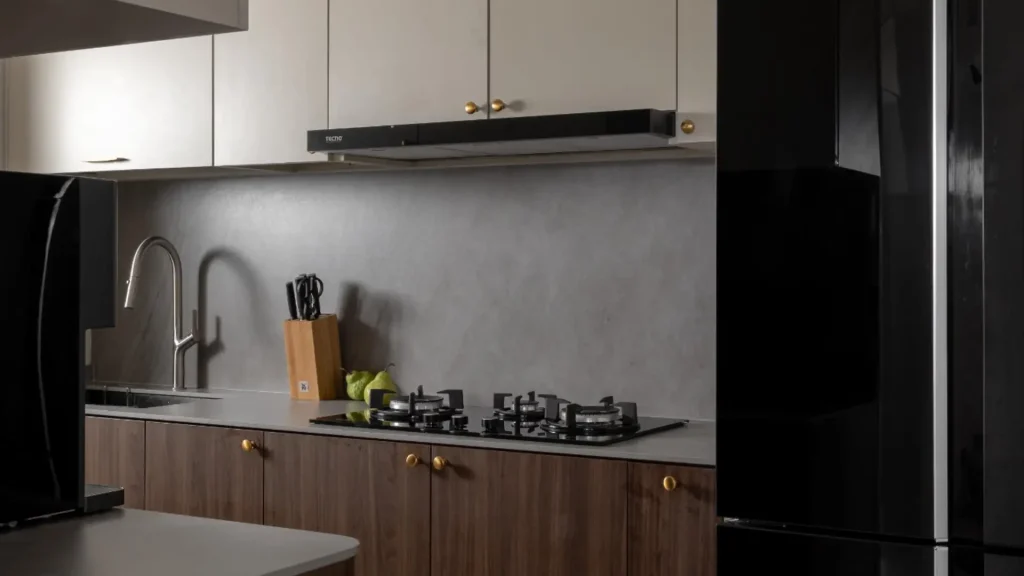 Walnut and brass kitchen renovation with micro-cement backsplash by 6AM Spaces Singapore