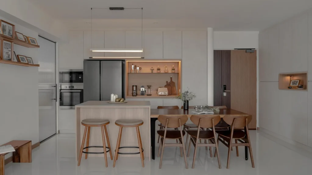Minimalist kitchen and dining area with clean cabinetry, timber stools, and warm lighting by 6AM Spaces