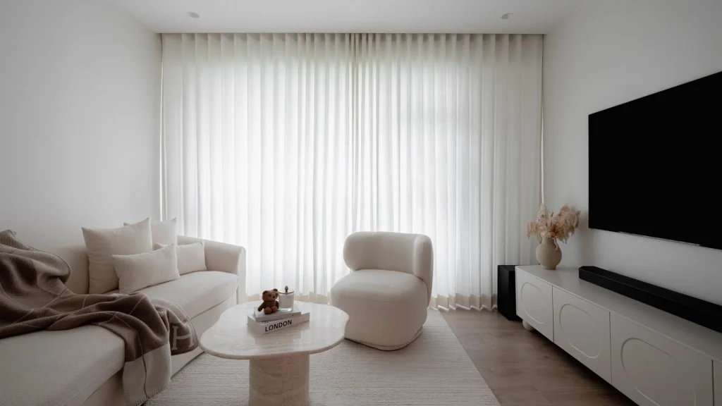Serene minimalist living room with neutral tones, sheer curtains, and natural light by 6AM Spaces