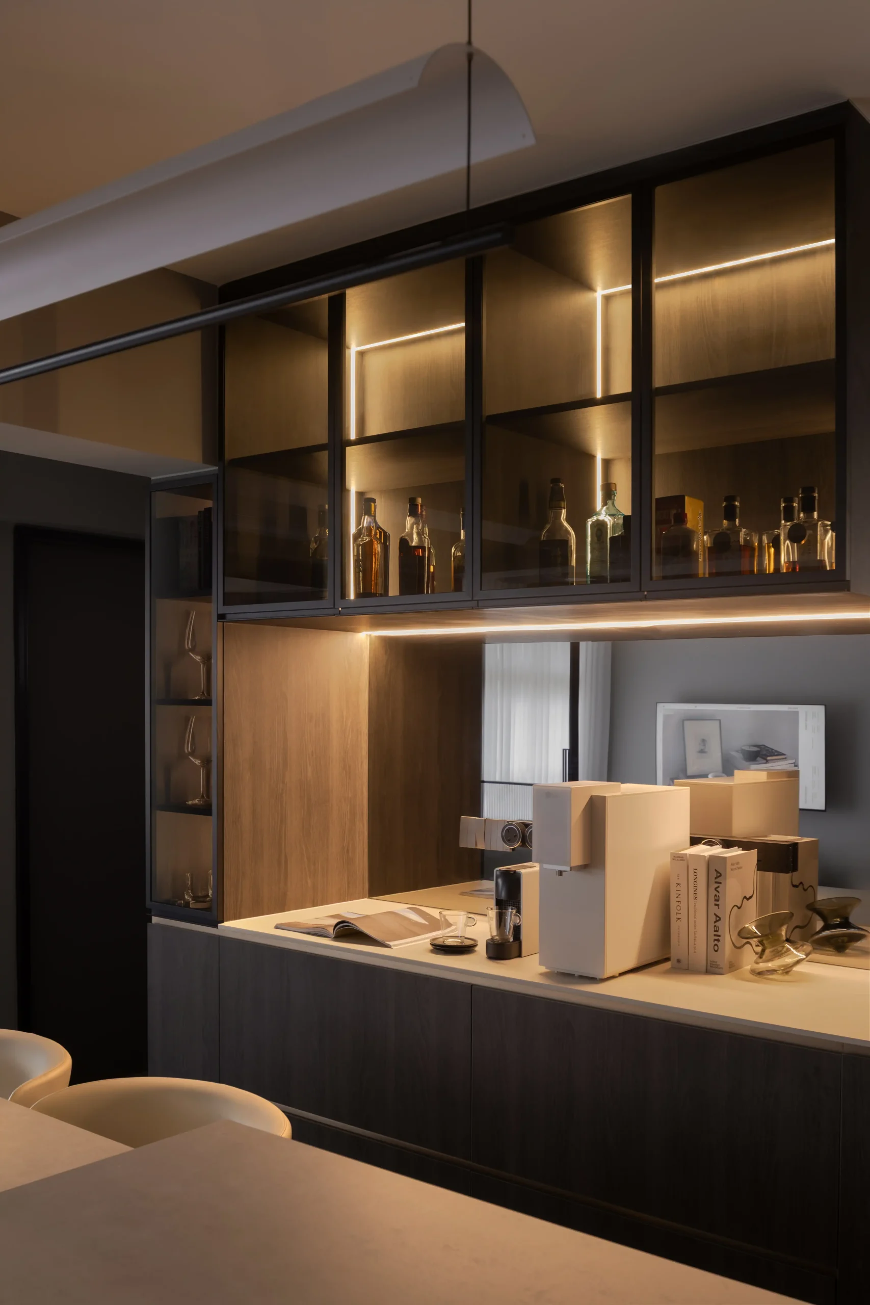 home bar station featuring sleek dark wood cabinetry, an integrated mirror backsplash, and glowing amber LED accent shelf lighting.