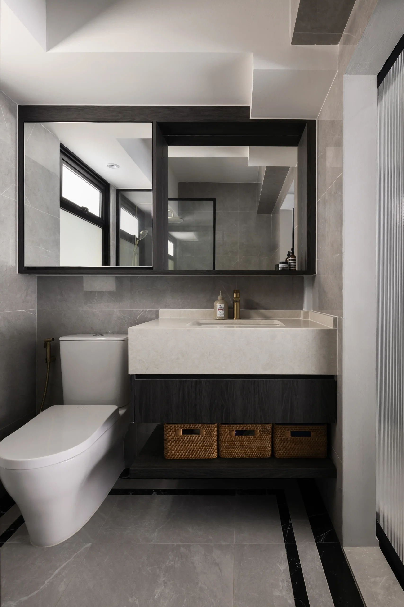 A dark luxury interior powder room featuring a floating dark wood vanity with woven storage baskets, light marble countertops, and a black-framed mirror cabinet.