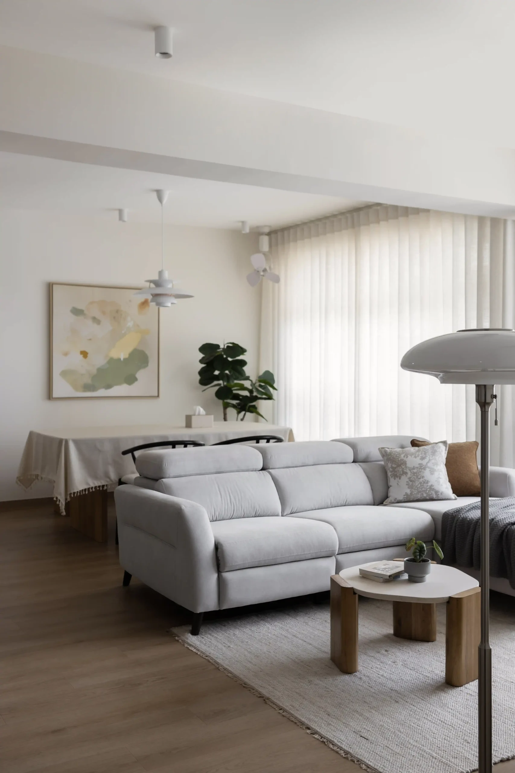Minimalist Japandi interior design living room featuring a light grey sectional sofa, wooden coffee table, and large abstract wall art.