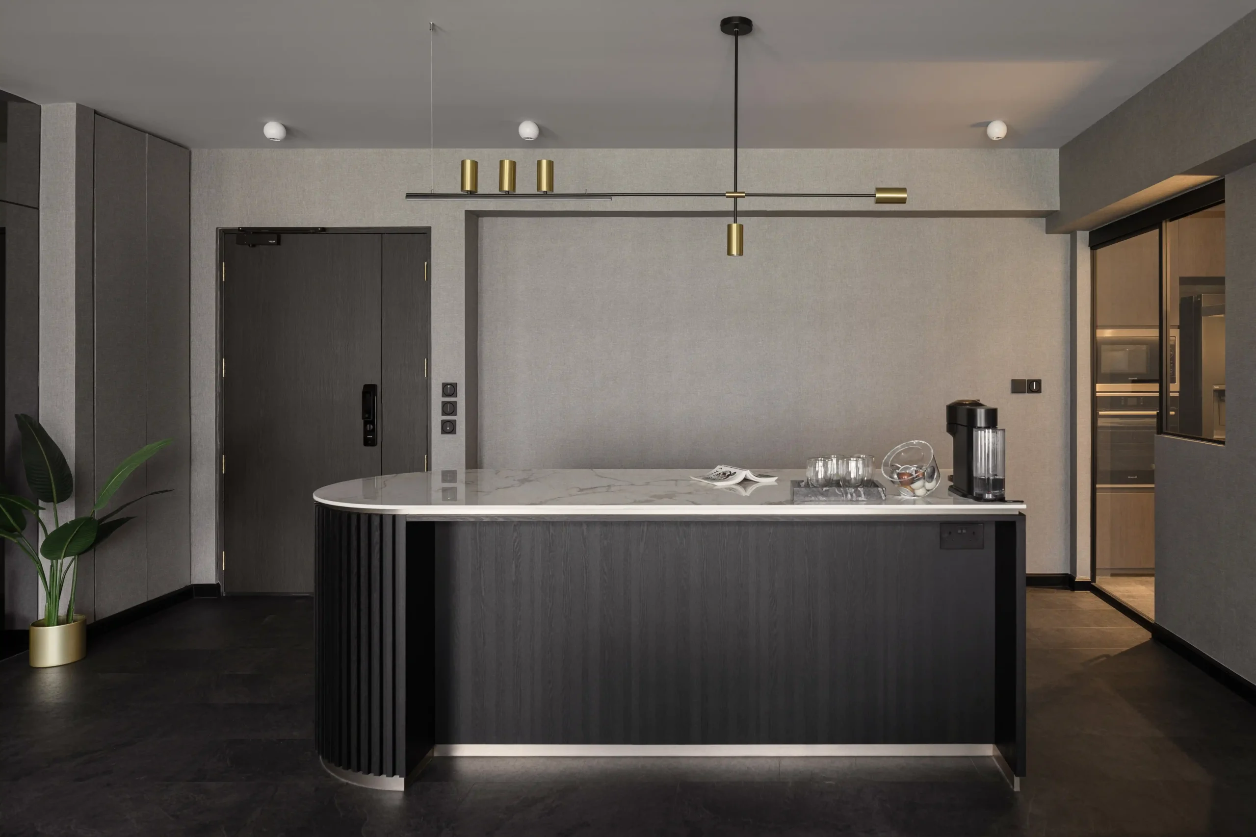 Modern luxury apartment design showing a sleek black kitchen island, minimalist pendant light, and textured grey walls.