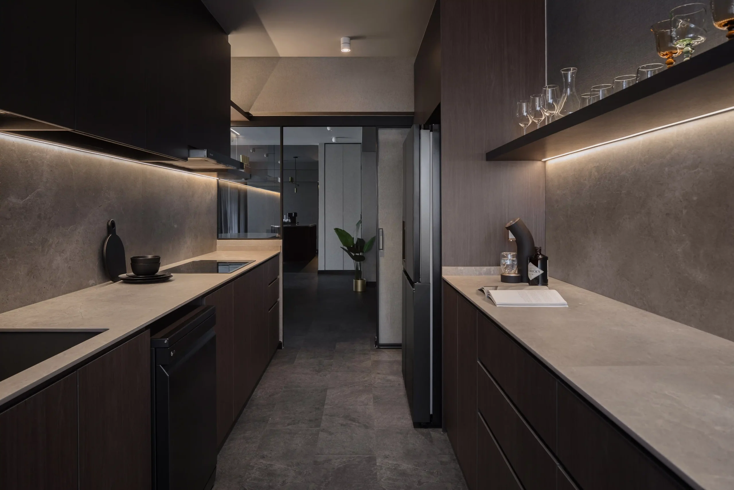Dark galley kitchen with stone texture backsplashes, integrated appliances, and under-cabinet LED strip lighting.