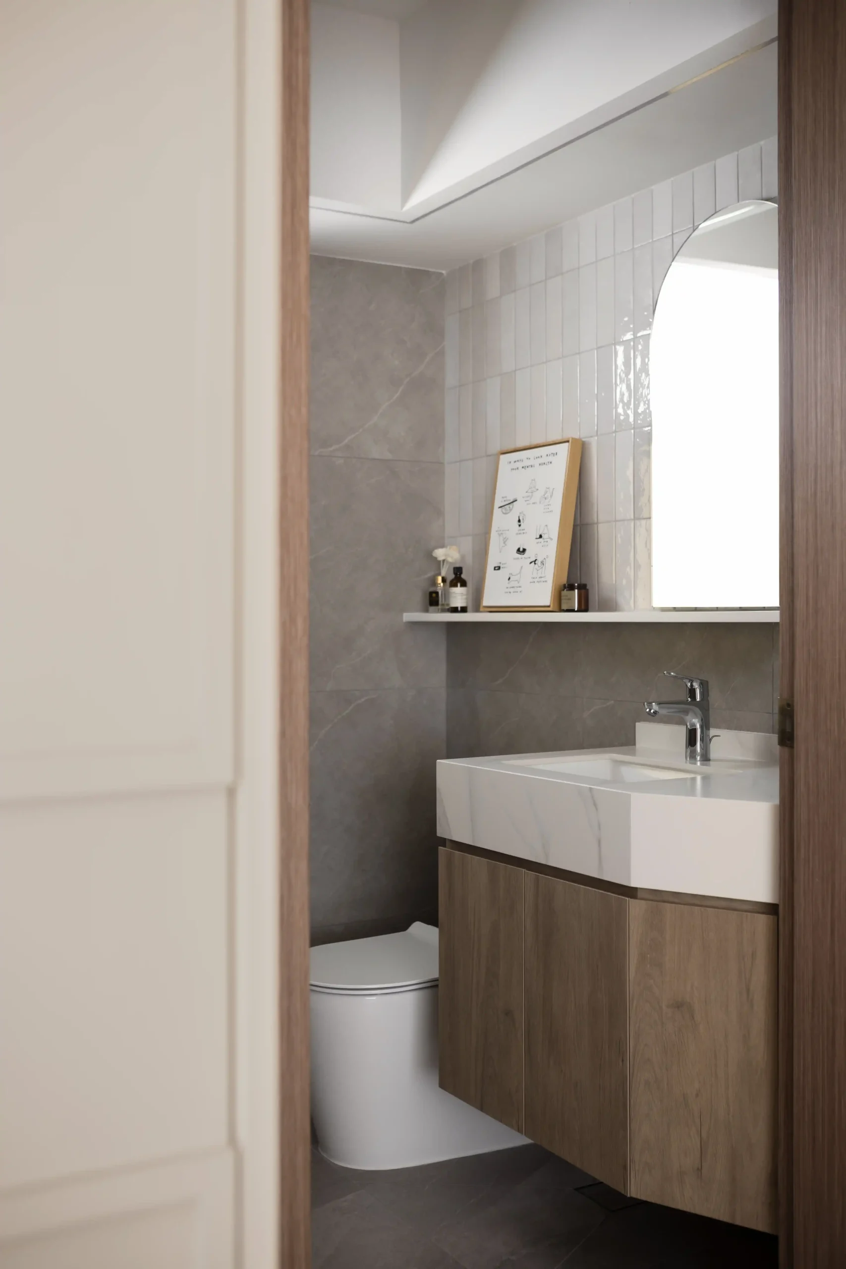 Floating wooden bathroom vanity and arched mirror in a calm, minimalist condo