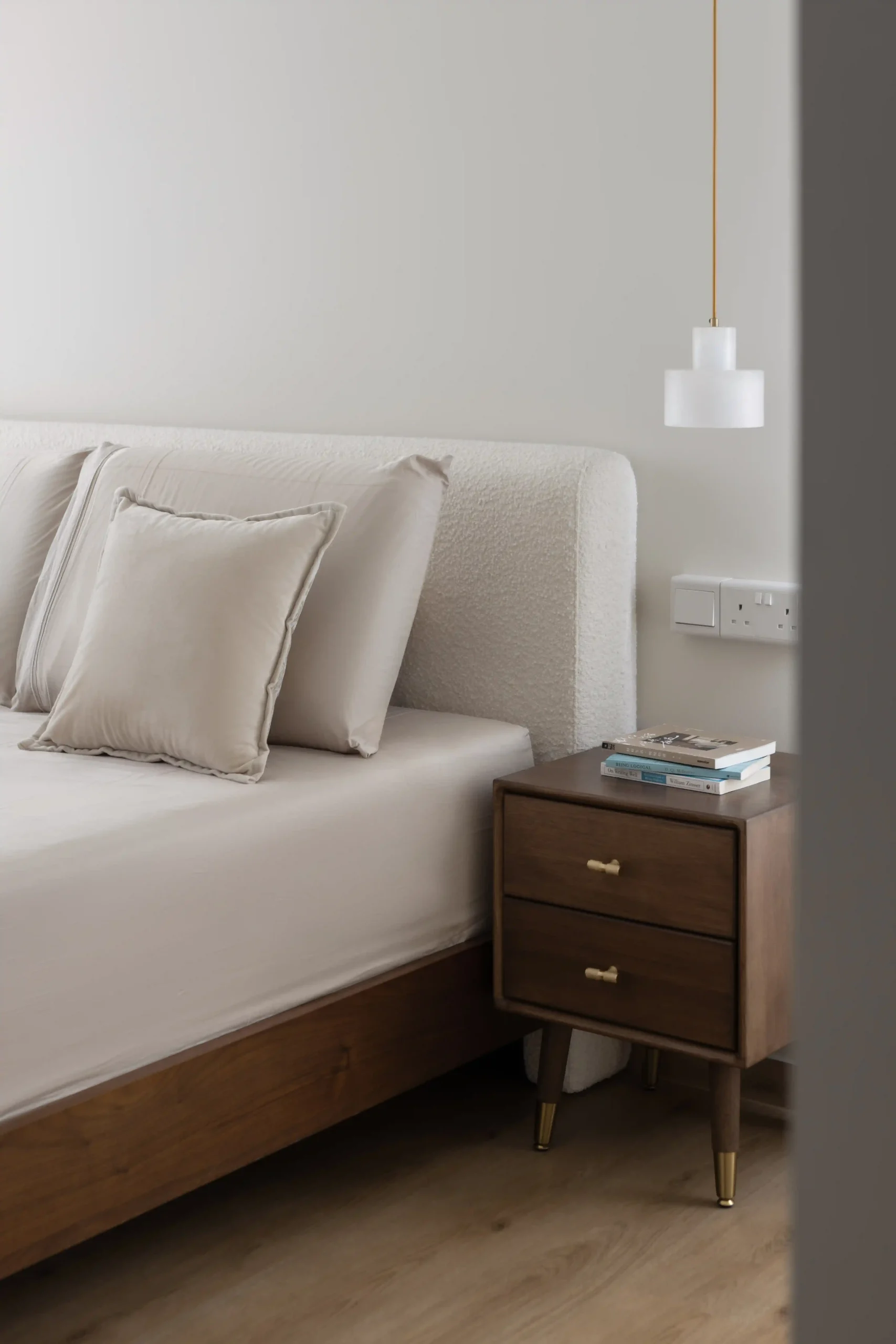 Cozy Japandi bedroom design featuring a wooden nightstand and bouclé headboard.