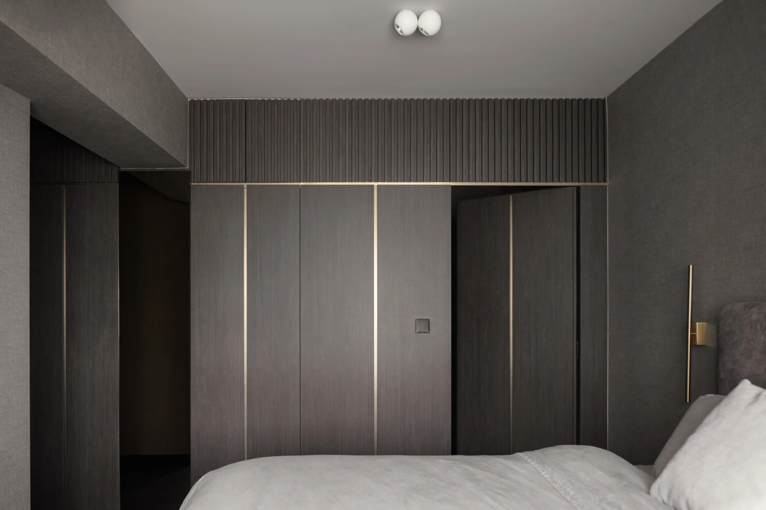 Modern luxury apartment design showcasing a hidden closet door integrated into custom dark wood bedroom paneling
