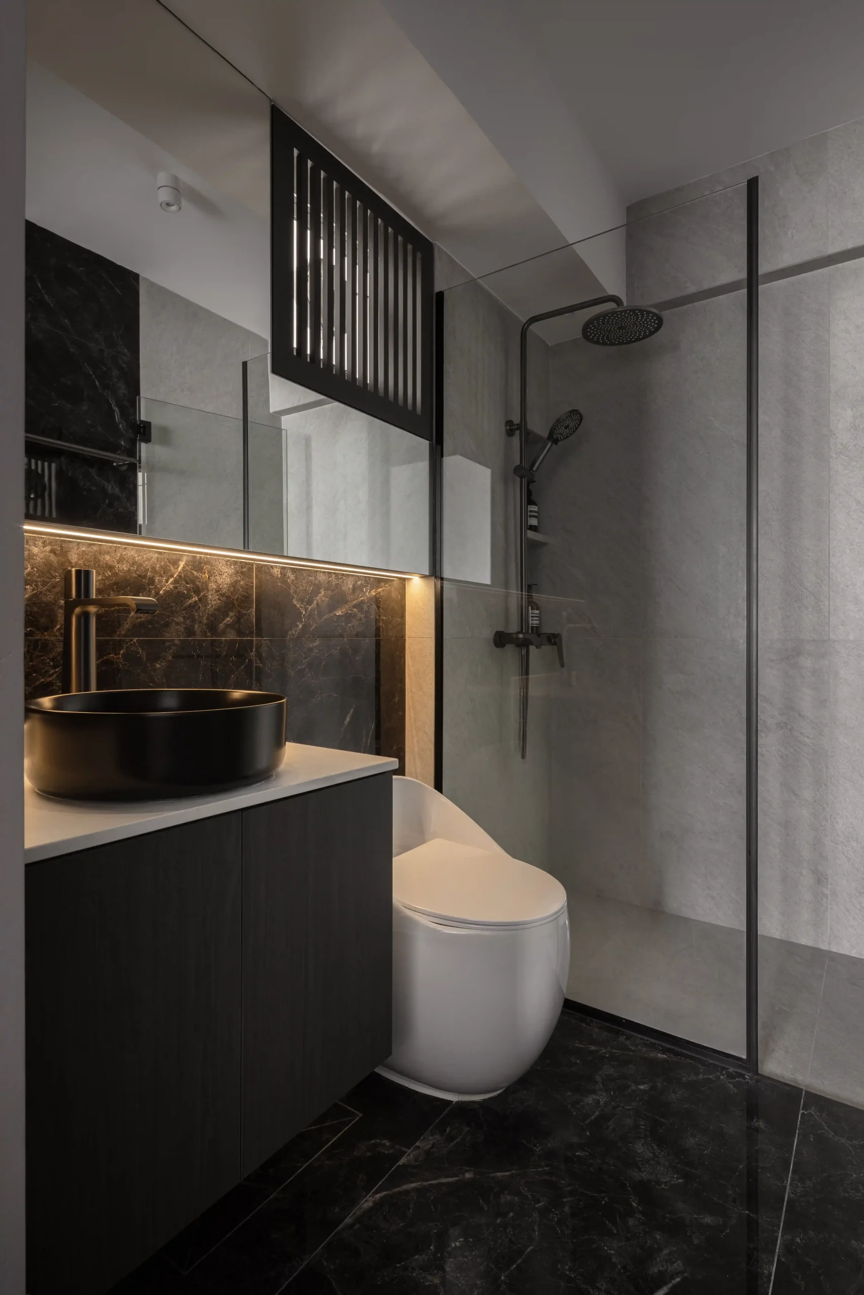 Luxury contemporary bathroom design with black marble flooring, a matte black vessel sink, and a glass walk-in shower.