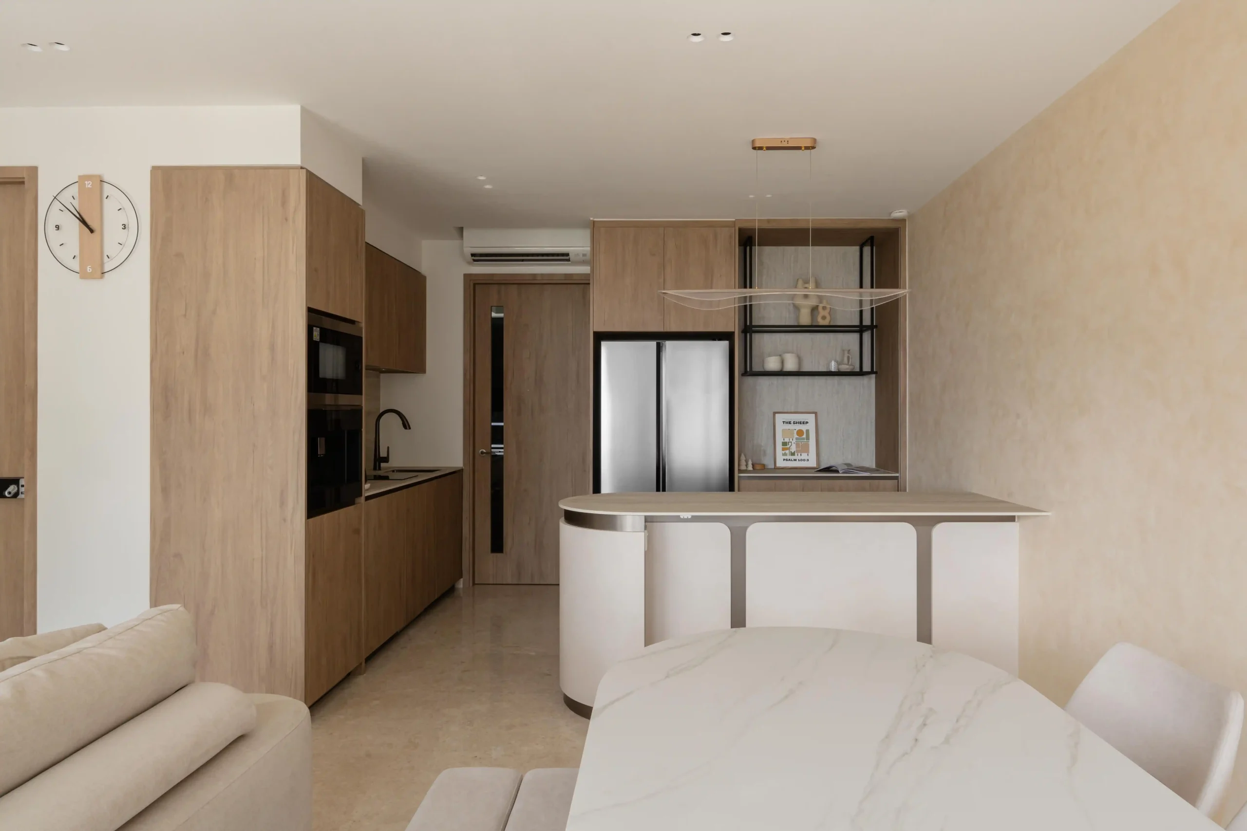 An open-plan japandi interior with warm wood cabinetry, a curved white dining island, marble table, and thoughtfully styled open shelving