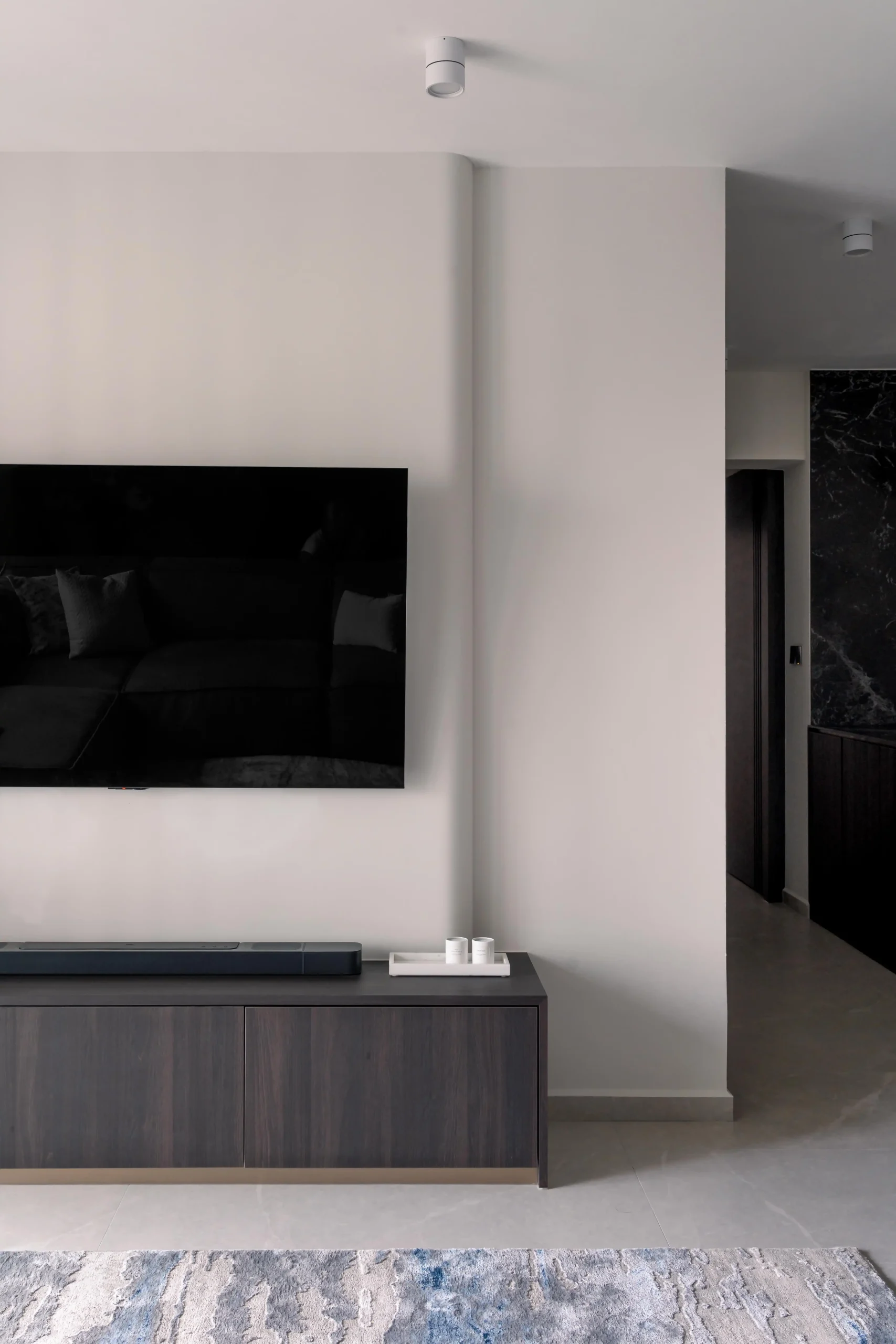 Minimalist TV wall with wall-mounted flatscreen and low-profile dark wood media console in modern interior design