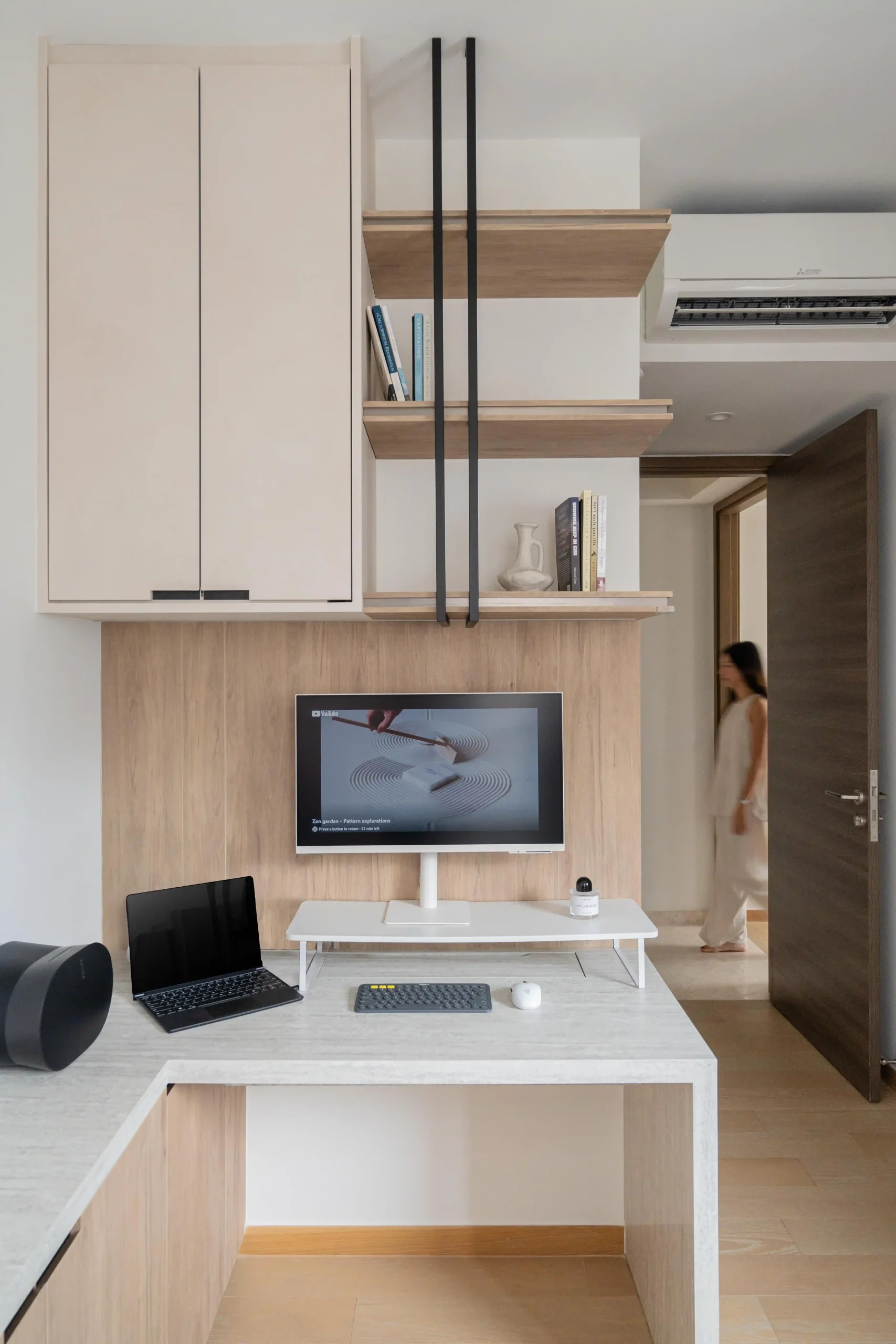  minimalist japandi-inspired home office with light wood floating shelves, built-in storage, a clean desk setup, and a zen garden display on screen