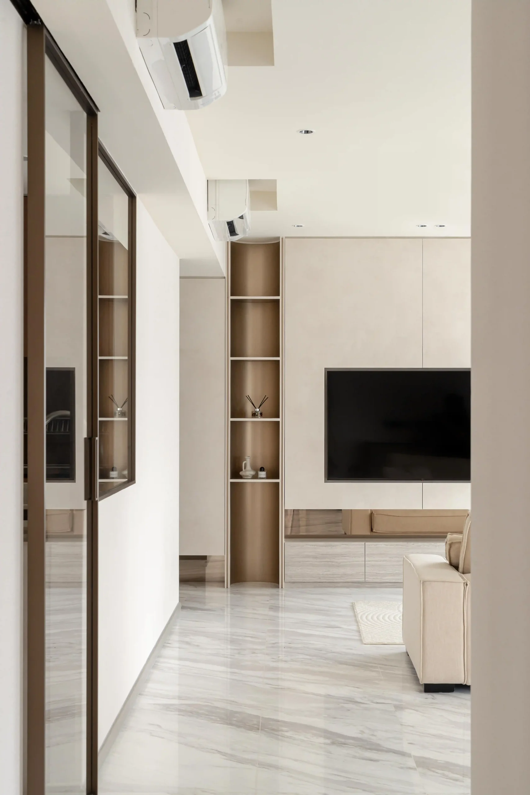 Hallway view featuring open bronze-interior display shelving, flush cabinetry, and seamless flow into the living room TV feature wall