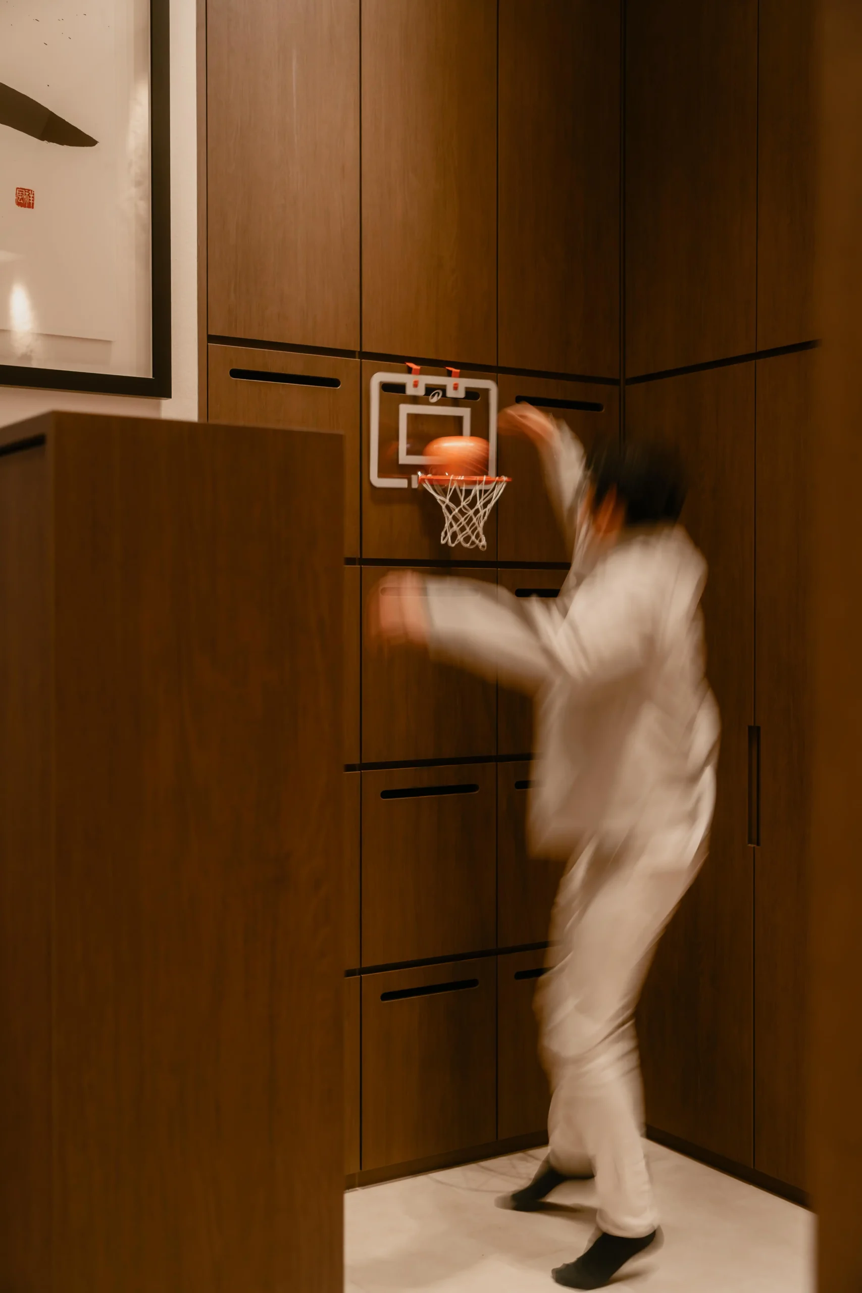 A mini indoor basketball hoop mounted to a sleek walnut cabinet wall inside Sumspace Studio.