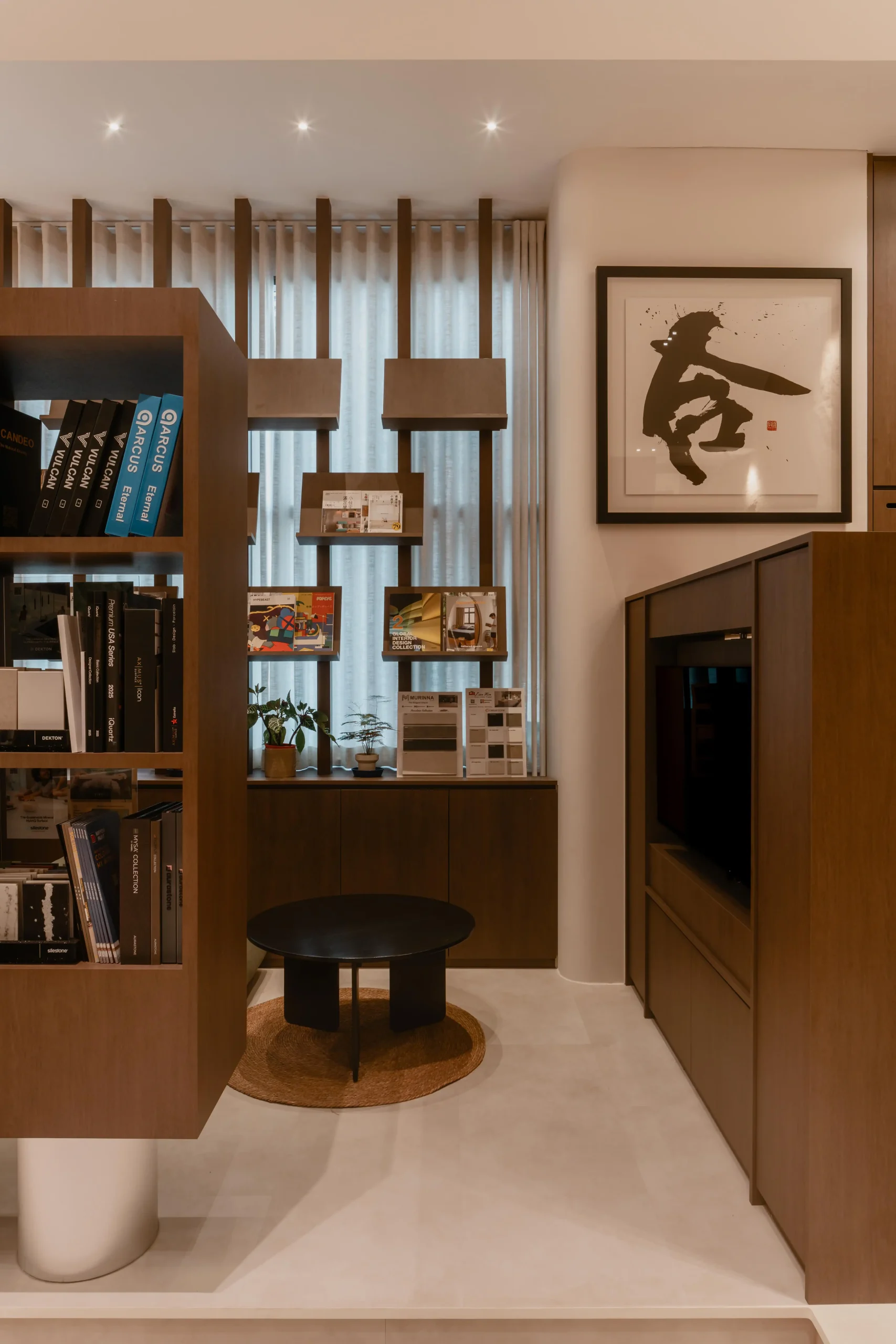 A small consultation area at Sumspace Studio with a walnut shelf unit, black coffee table, and framed artwork.