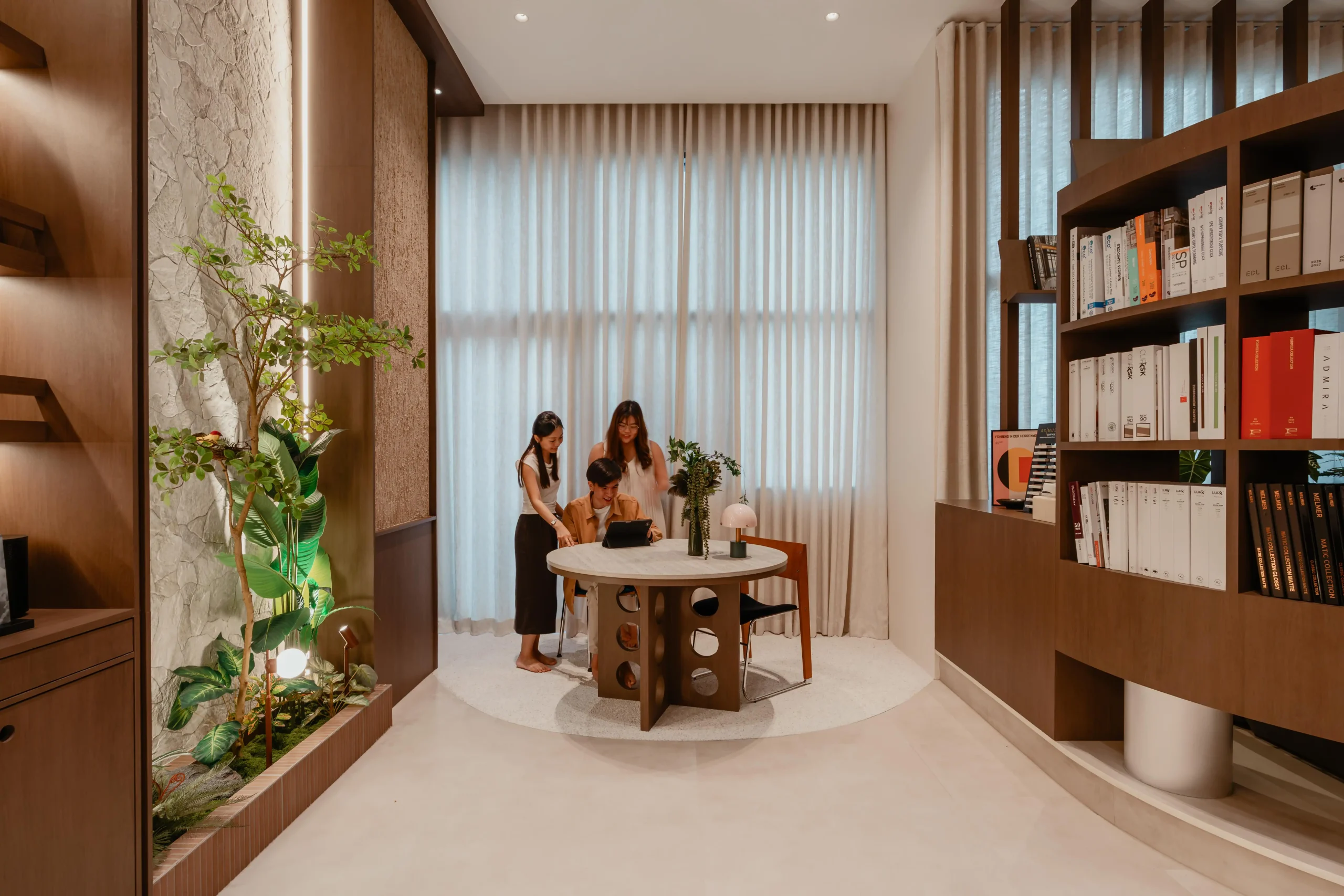 A bright meeting space with a table, custom walnut shelving, and a decorative indoor plant.