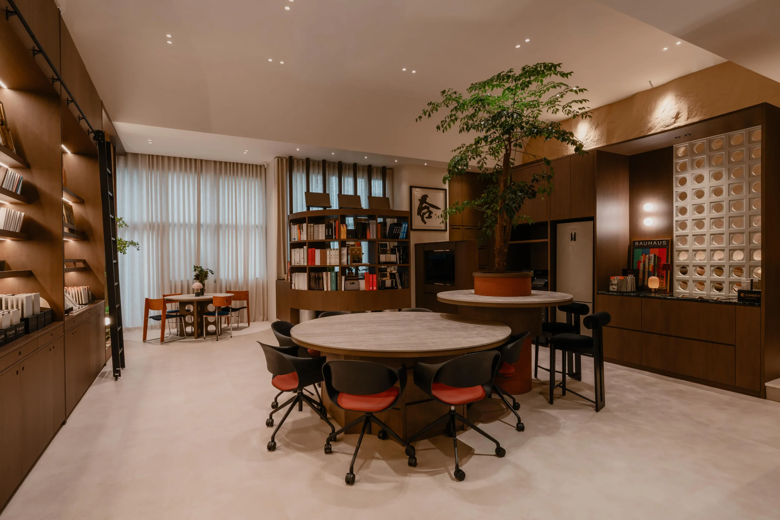 Overview of Sumspace Studio showing an open layout with round tables, an indoor tree, and warm lighting.