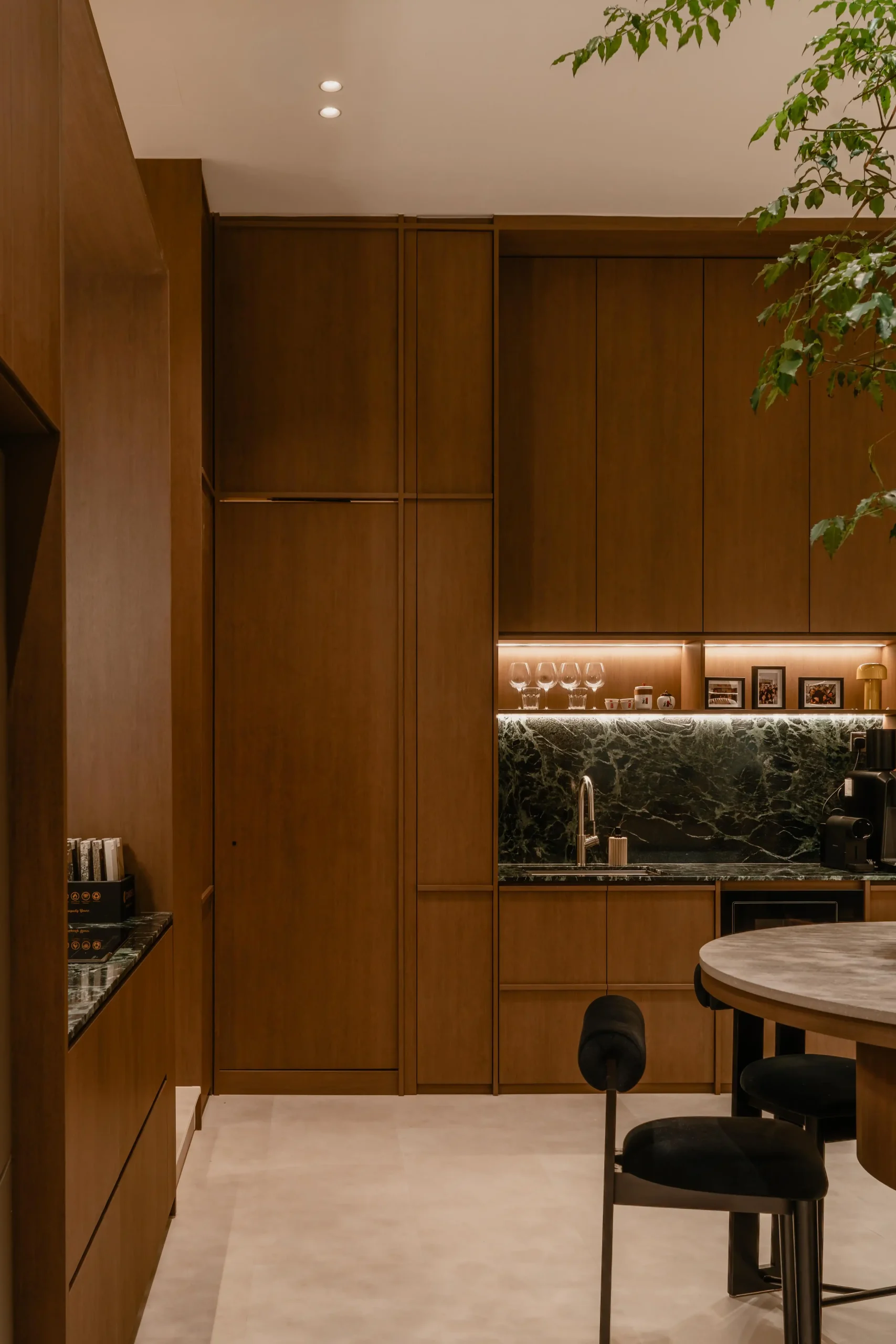 Modern studio pantry with tall walnut storage cabinets, a green marble counter, and minimalist bar seating.