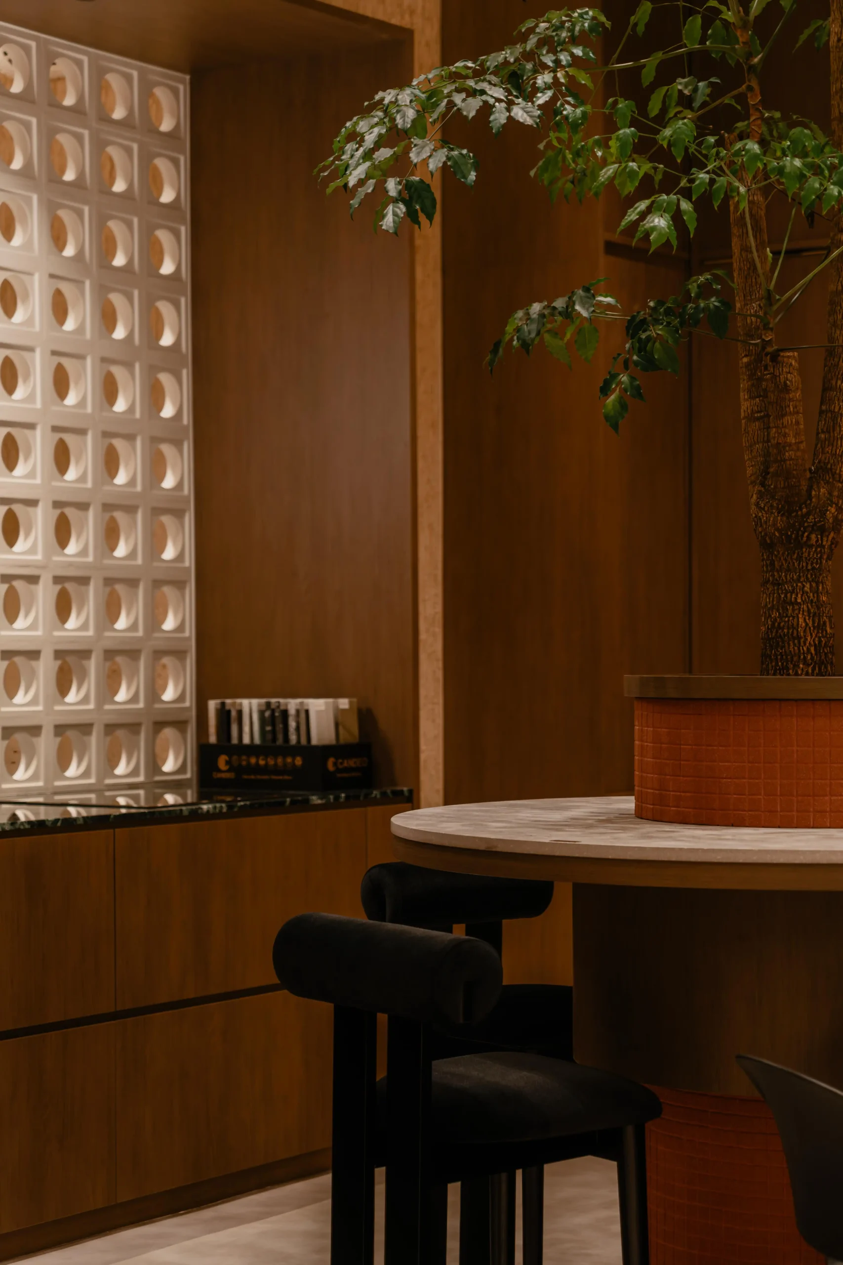 High bar seating and a round stone table placed near a white breeze block feature wall.