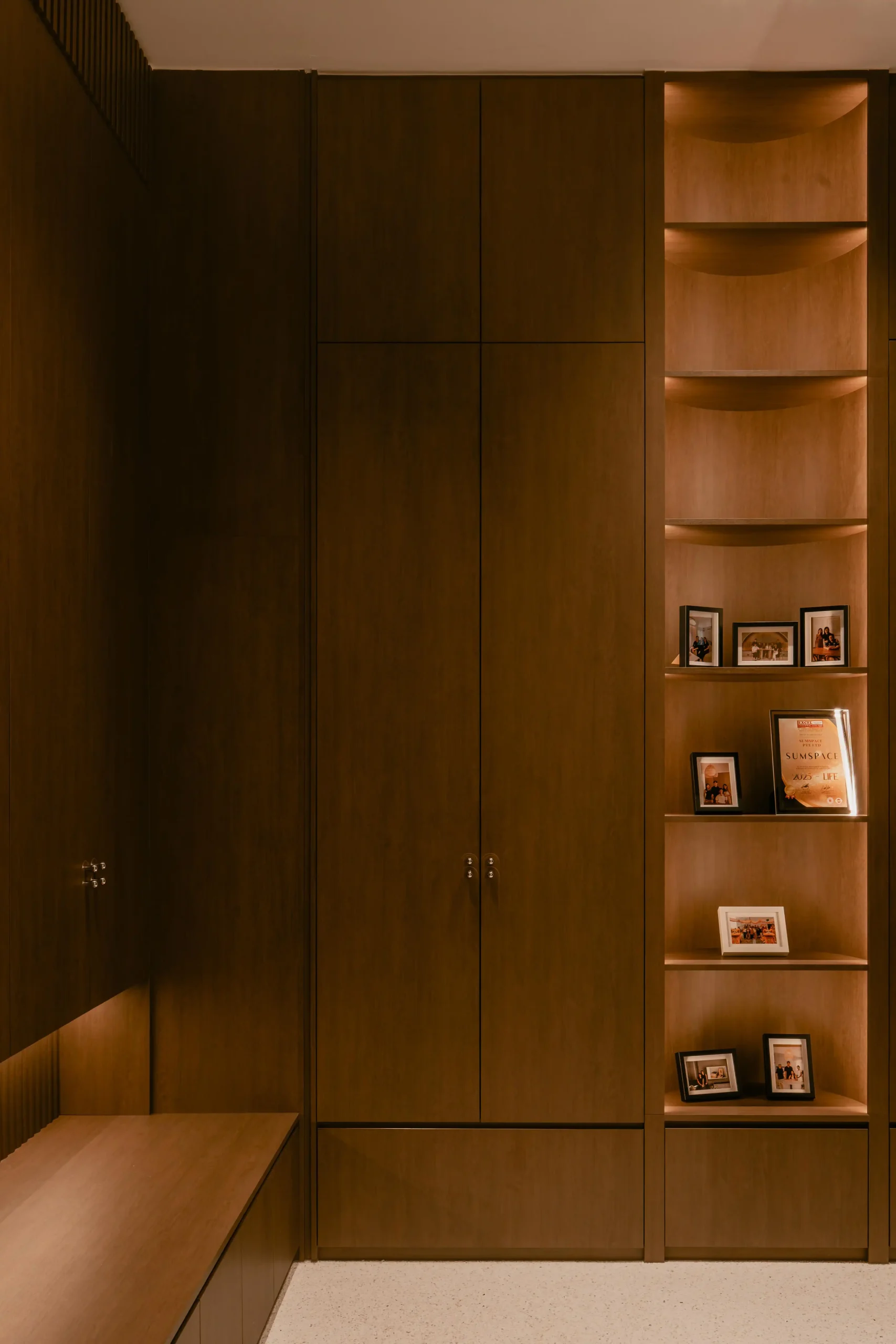 Floor-to-ceiling walnut cabinetry at Sumspace Studio with built-in shelves displaying framed team photos.
