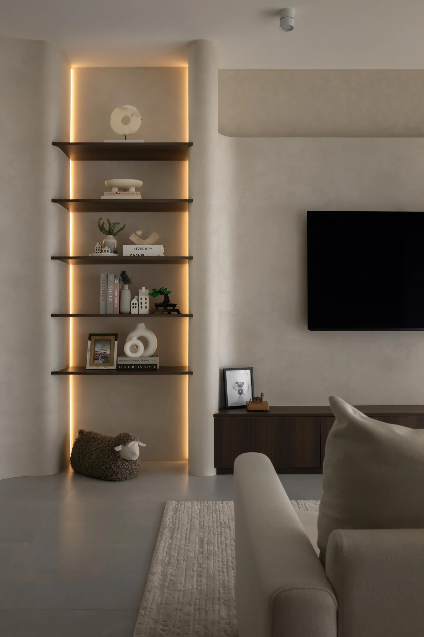 Warm backlit open shelves between curved plaster walls in a modern japandi space.