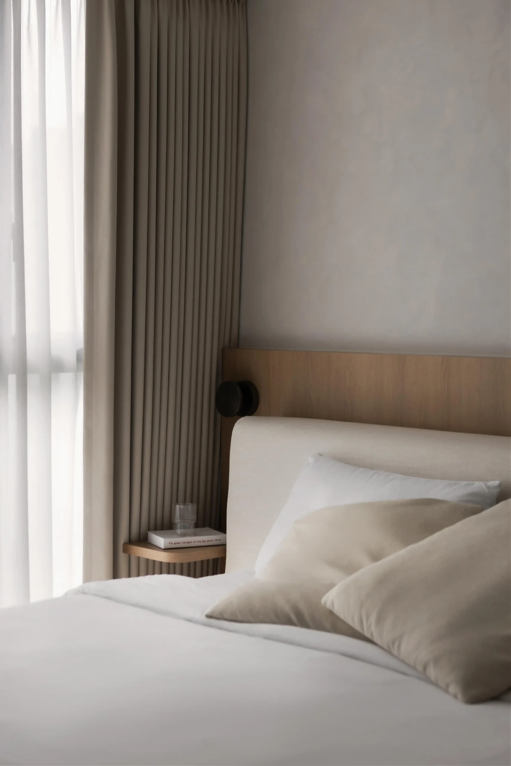 Close-up of a neutral bed and light wood paneling