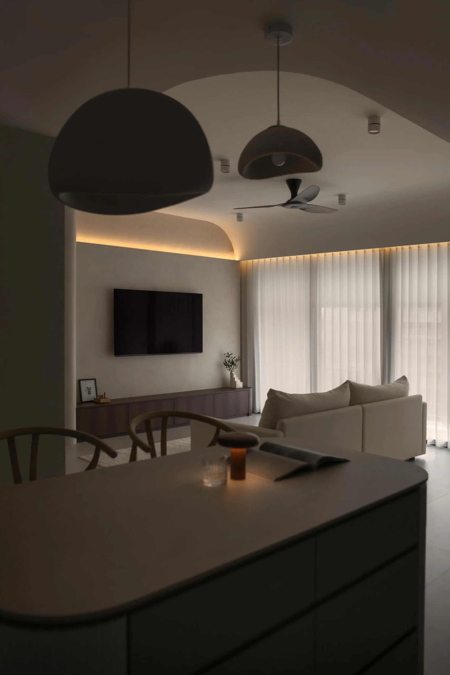 Evening view of a modern japandi living area with soft ambient tray lighting.